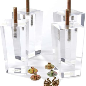 以下が含まれることがあります： 金色のネジと金属製の取り付けプレートが付いた透明なアクリル製の家具脚が4本。脚は正方形で、斜めになっている。セットには、金色のネジの袋も含まれている。