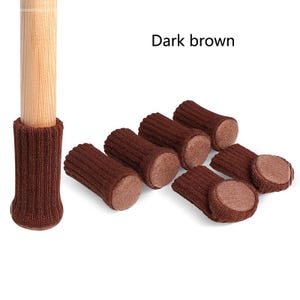 May include: Dark brown furniture leg protectors with felt pads. The protectors are made of a knitted fabric and are designed to protect floors from scratches.