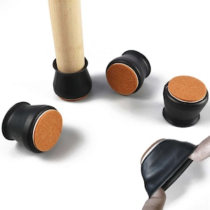 May include: Black furniture leg protectors with a felt base. These protectors are made from a flexible, rubber-like material and are designed to fit over furniture legs. The felt base helps to protect floors from scratches and marks.