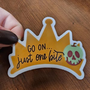 May include: A yellow crown sticker with the text "GO ON... just one bite" and a green apple with a skull face and red eyes.