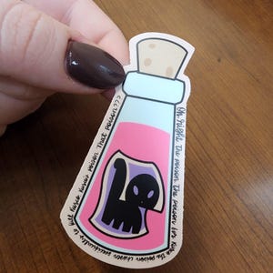 May include: A sticker of a pink potion bottle with a black cat inside. The text on the sticker reads "Oh, right. The poison. The poison for Kusco. The poison chosen specifically to kill Kuzco. Kusco's poison That poison??"