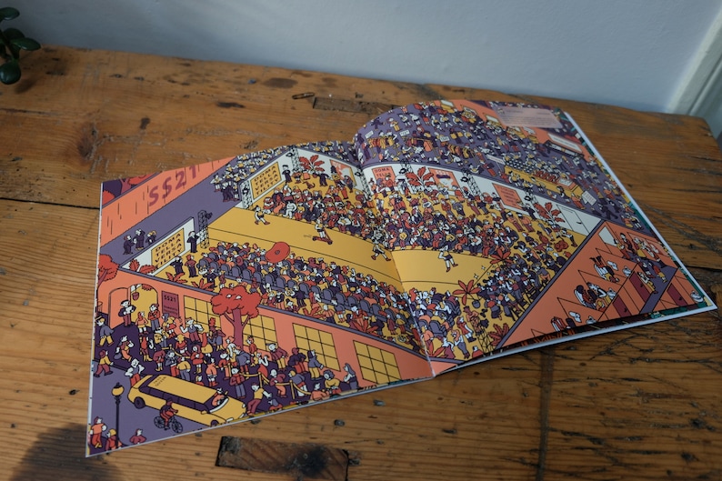 Może przedstawiać: Otwarta książka z kolorową ilustracją zatłoczonej sceny. Ilustracja jest pełna ludzi, budynk&oacute;w i drzew. Książka jest otwarta na stronie z tekstem "SS21" na budynku.