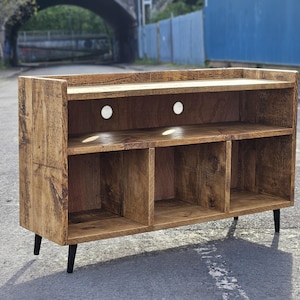 A rustic vinyl storage unit crafted from reclaimed wood, featuring designated spaces for a turntable and amplifier, along with shelves for organizing vinyl records, combining functionality and vintage charm in a cozy music corner