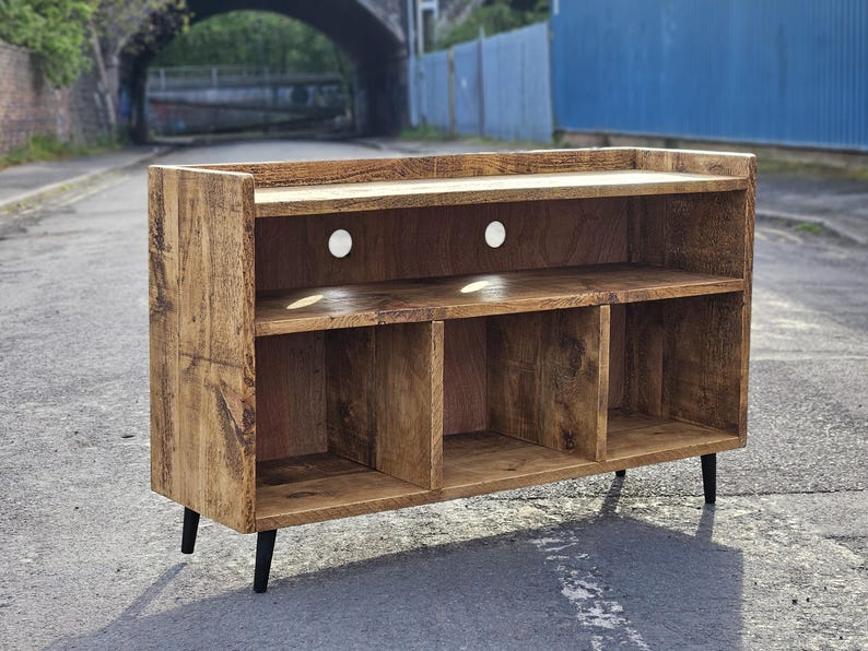 A rustic vinyl storage unit crafted from reclaimed wood, featuring designated spaces for a turntable and amplifier, along with shelves for organizing vinyl records, combining functionality and vintage charm in a cozy music corner