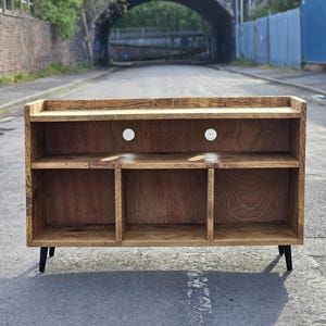 A rustic vinyl storage unit crafted from reclaimed wood, featuring designated spaces for a turntable and amplifier, along with shelves for organizing vinyl records, combining functionality and vintage charm in a cozy music corner