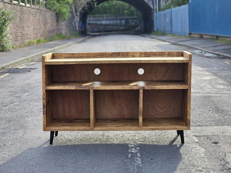 A rustic vinyl storage unit crafted from reclaimed wood, featuring designated spaces for a turntable and amplifier, along with shelves for organizing vinyl records, combining functionality and vintage charm in a cozy music corner