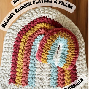 May include: Hand crocheted rainbow playmat and pillow set. The playmat is a large, round, crocheted rainbow with a smaller, round, crocheted rainbow pillow in the center. The playmat is made with chunky yarn in shades of white, yellow, orange, red, pink, blue, and green. The pillow is made with the same yarn in the same colors. The playmat and pillow are both made with a simple crochet stitch. The playmat is perfect for a child's playroom or bedroom. The pillow is perfect for cuddling or playing with.