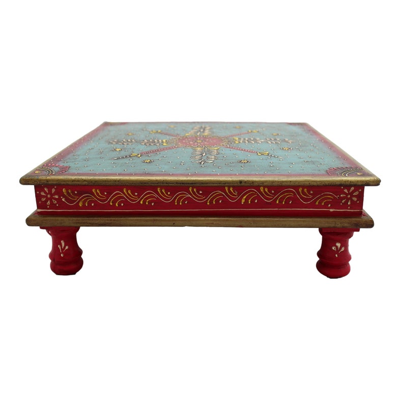 May include: A square wooden table with hand-painted floral designs in gold, red, and blue on a teal background. The table has four red legs with a decorative design.