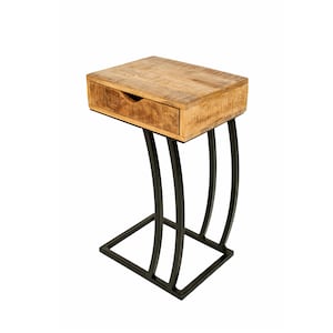 May include: A small side table with a natural wood top and a single drawer. The table has a black metal base with curved legs and a rectangular base. The wood has a warm, light brown colour. The table is approximately 60 cm high.