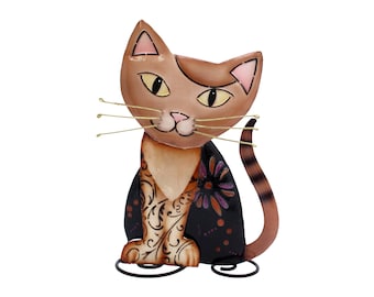 Può includere: Una statuetta di gatto in metallo marrone e nero con un design floreale sul corpo. Il gatto è seduto con la coda arrotolata intorno alle gambe. Il gatto indossa una giacca con motivi neri e bianchi con un fiore rosa sul retro.