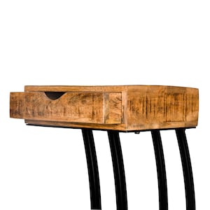 May include: A wooden desk with an open drawer, revealing the wood's natural grain. The desk is supported by black, curved metal legs, offering a modern, minimalist design. The desk's dimensions are not visible.