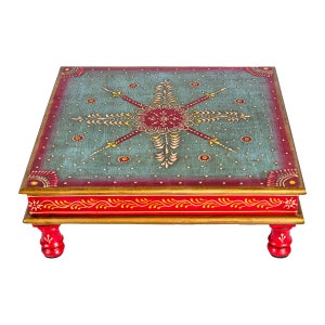 May include: A square wooden table with four legs, painted in red and gold with a blue and red floral design on the top.
