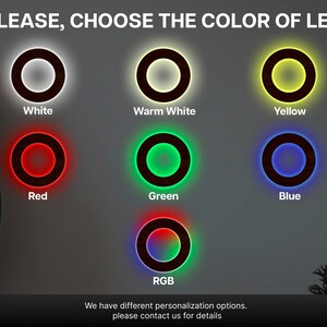May include: A display showing seven circular wooden rings with LED lighting options. The text reads PLEASE, CHOOSE THE COLOUR OF LED, with labels for White, Warm White, Yellow, Red, Green, Blue, and RGB. A footer states We have different personalisation options.