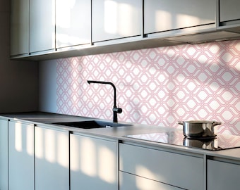 May include: A kitchen backsplash featuring a repeating white and pink geometric ogee pattern. The backsplash is installed behind a black faucet, a stainless steel sink, and a stainless steel pot resting on a smooth, dark countertop.