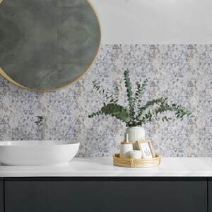 May include: A bathroom vanity with a white sink, a round mirror with a wooden frame, and a tray with a plant, a bottle of soap, and a picture frame. The wall behind the vanity is covered in a geometric pattern of grey and white triangles.