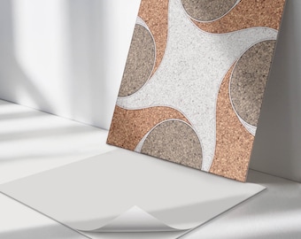 May include: A square adhesive tile featuring a repeating pattern of curved shapes in light brown cork, dark grey speckled material, and a central white speckled section. The tile has a white backing sheet partially peeled away at the bottom corner.