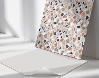 May include: A square adhesive sheet featuring a repeating terrazzo pattern with irregular fragments in shades of terracotta, sage green, dark charcoal, and white set against a light beige background, with a corner peeled back to reveal the white backing.
