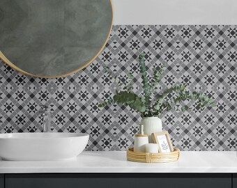 May include: A bathroom vanity area featuring a white oval vessel sink, a chrome faucet, and a round mirror with a thin gold frame. The wall is covered in a gray and white geometric tile pattern. A white vase with eucalyptus sits on a tray.