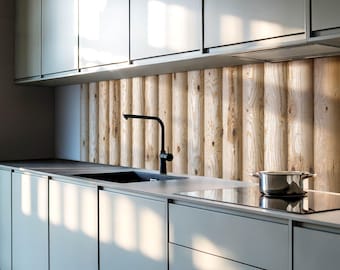 May include: A modern kitchen featuring matte light gray flat-panel cabinetry, a dark gray countertop, and a black faucet. The backsplash is composed of vertical, light-toned wooden logs with visible grain and knots, illuminated by natural light.