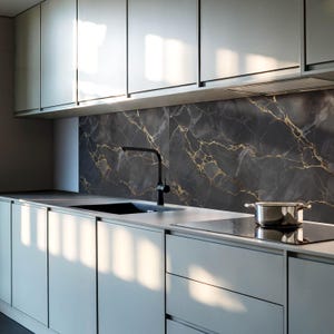 Puede incluir: Una cocina moderna con gabinetes blancos y un salpicadero de mármol negro con vetas doradas. Un grifo negro está montado sobre un fregadero de acero inoxidable. Una encimera de cocina negra es visible en el fondo.