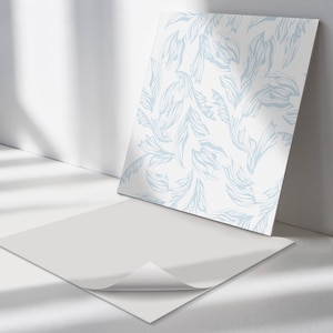 May include: A white sheet of paper with a light blue floral pattern printed on it. The paper is folded in half and the top layer is peeled back to reveal the adhesive backing.