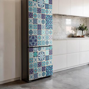 Op de afbeelding: Een koelkast met een decoratief tegelontwerp in tinten blauw, turquoise en paars. Het patroon bestaat uit vierkante tegels met bloemen en geometrische motieven, wat een levendige, artistieke uitstraling geeft.