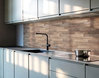May include: A modern kitchen featuring matte light gray cabinetry with flat-panel doors, a black gooseneck faucet over a rectangular sink, and a textured light brown wood-look backsplash. A stainless steel pot sits on a black glass stovetop.