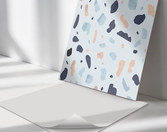 May include: A square adhesive sheet featuring a light blue background with a scattered pattern of irregular shapes in dark navy blue, pale blue, and soft peach. The sheet has a white backing paper partially peeled back at the bottom corner.