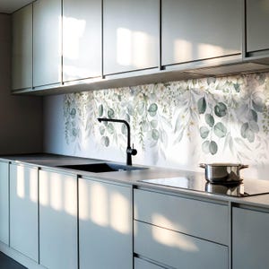 Può includere: Una cucina moderna con armadi grigi e uno schienale bianco con un design floreale ad acquerello di foglie verdi e fiori bianchi.