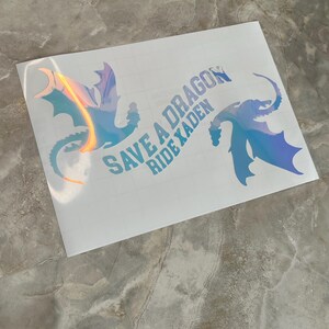 May include: A white sticker with two iridescent blue dragon silhouettes and the text "Save a Dragon Ride a Xaden".