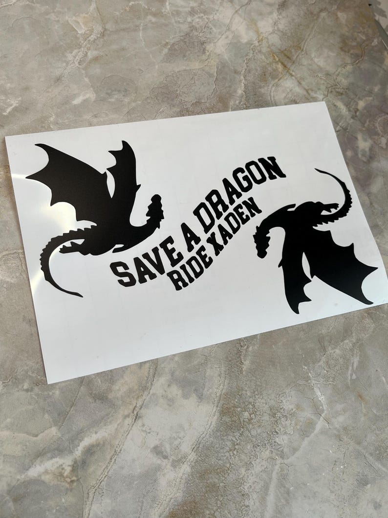 May include: A white sticker with two black dragon silhouettes and the text "Save a Dragon Ride a Kaden".