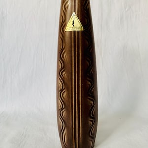 Könnte beinhalten: Eine braune Keramikvase mit einem wellenförmigen Muster und zwei vertikalen Linien. Die Vase hat ein goldenes Etikett mit dem Text "Langeland Keramik Danmark".