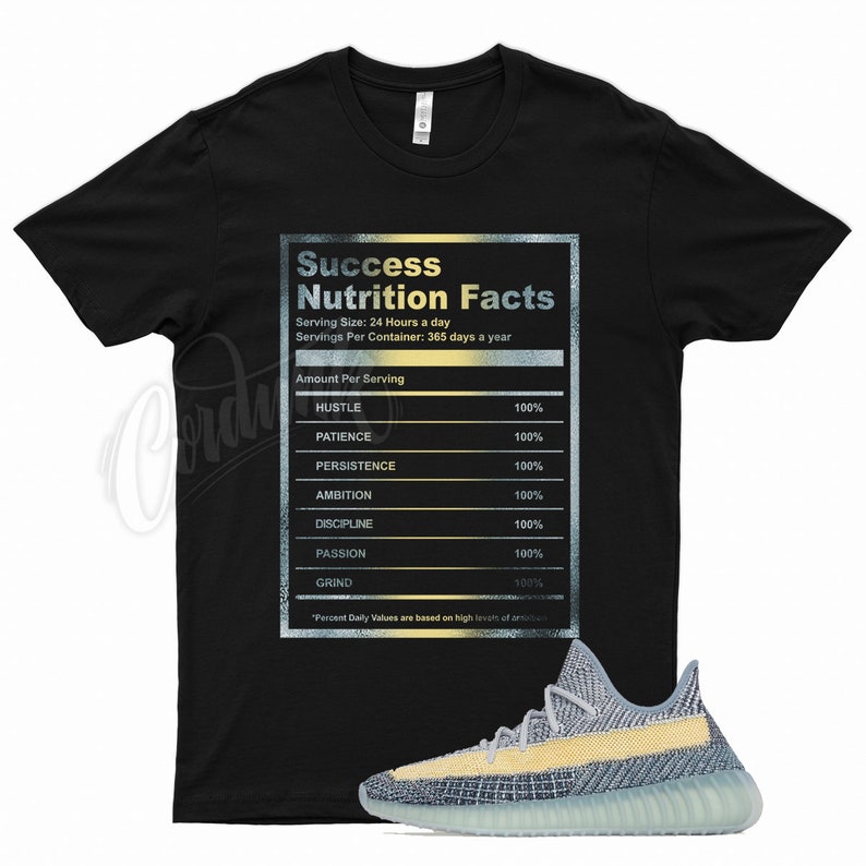 May include: Black t-shirt with a gold and silver graphic that reads "Success Nutrition Facts" with a list of qualities needed for success, including hustle, patience, persistence, ambition, discipline, passion, and grind. The t-shirt is paired with a pair of light blue and yellow sneakers.