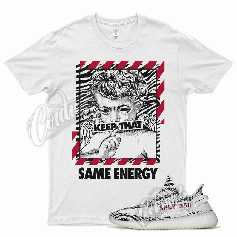 May include: White t-shirt featuring a black and white graphic of a cherub with the text "KEEP THAT" and "SAME ENERGY". A pair of black and white striped sneakers with "SPLY-350" text is also in the image.