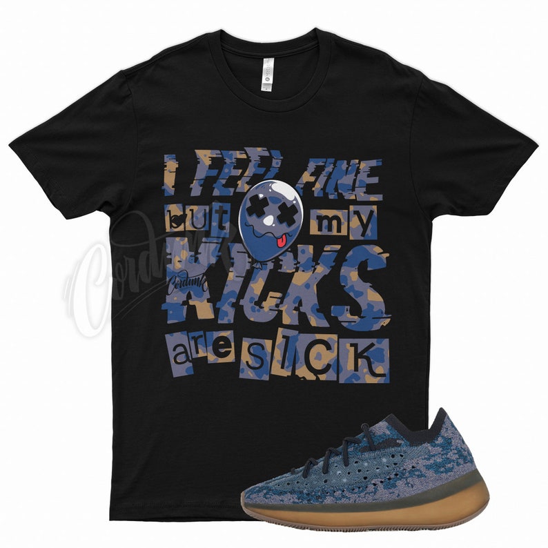 May include: Black t-shirt with a graphic print that says "I feel fine but my kicks are sick". The graphic features a blue cartoon face with a tongue sticking out. A pair of blue and brown trainers are in the bottom right corner of the image.