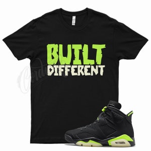 May include: Black t-shirt with the text "BUILT DIFFERENT" in green and white lettering. A black and green sneaker with a white sole is also pictured.