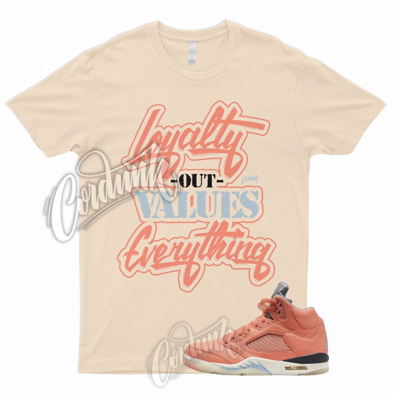 May include: A light peach colored t-shirt with the text "Loyalty Out Values Everything" in a pink and blue font. A pair of coral colored sneakers with a white sole.