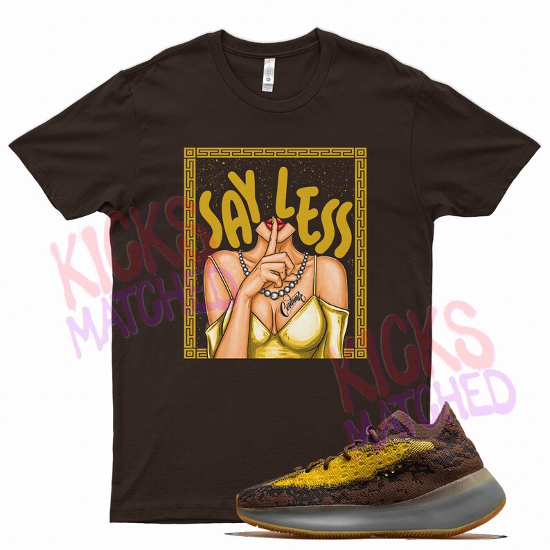 Puede incluir: Una camiseta marr&oacute;n con un gr&aacute;fico de una mujer con el dedo en los labios y el texto "Say Less" en letras doradas. El gr&aacute;fico est&aacute; rodeado por un marco dorado. Tambi&eacute;n se muestra un par de zapatillas marrones y amarillas.