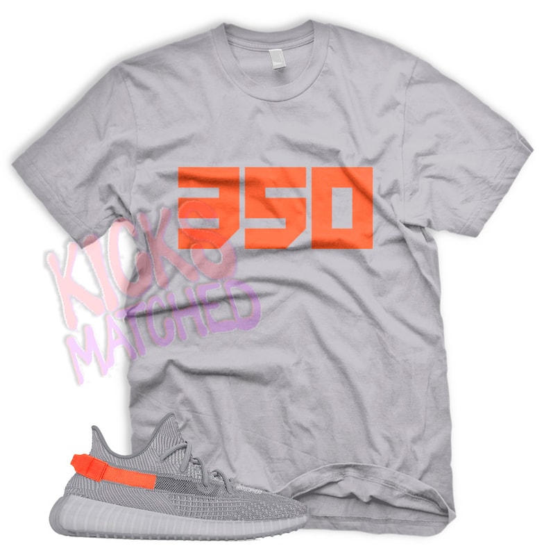 May include: A gray t-shirt with the number "350" printed in orange on the front. A pair of gray and orange sneakers are shown below the shirt.