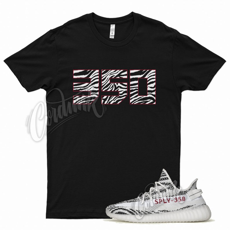 May include: Black t-shirt with a zebra print "350" graphic.  White and black zebra print sneakers with "SPLY-350" text.