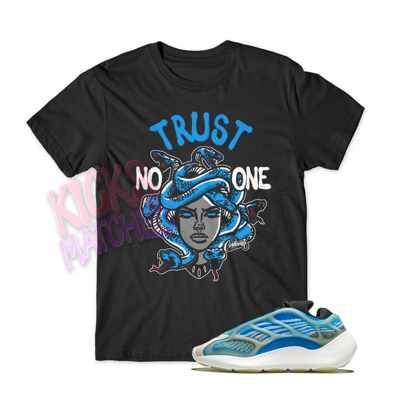 May include: Black t-shirt with a graphic of a Medusa head with snakes and the text "TRUST NO ONE".  A pair of blue and white sneakers are also pictured.