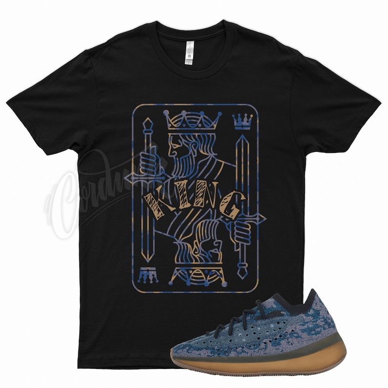 May include: Black t-shirt with a graphic of a king of spades playing card with the word "KING" written in gold. A pair of blue and brown sneakers with a speckled pattern.
