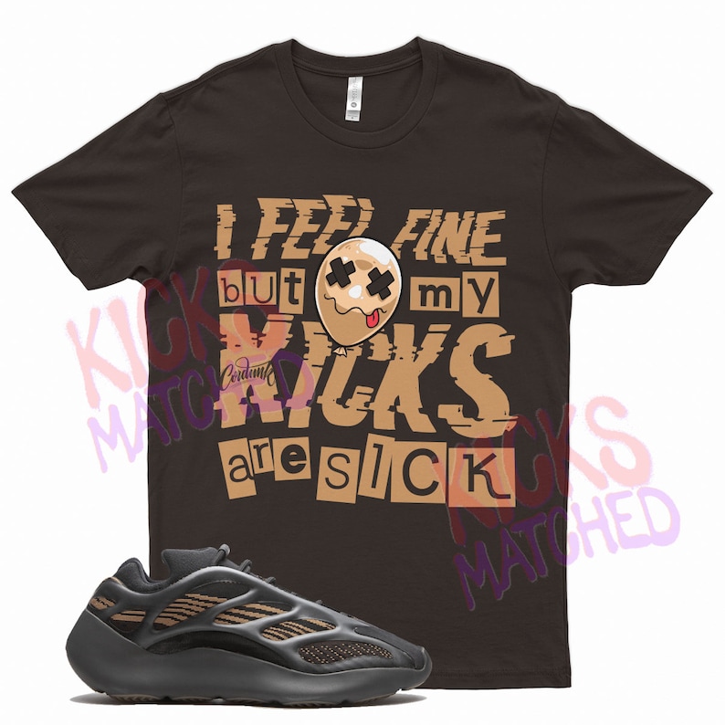 May include: A brown t-shirt with the text "I feel fine but my kicks are sick" in a distressed font. The text is surrounded by a cartoon image of a brown balloon with a face and a tongue sticking out. A pair of black and brown sneakers are in the foreground.