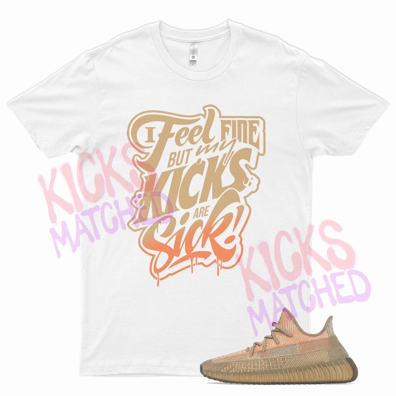 Puede incluir: Camiseta blanca con el texto "I Feel Fine But My Kicks Are Sick!" en letras naranja y marr&oacute;n. Debajo de la camiseta se muestra un par de zapatillas de deporte de color marr&oacute;n claro y marr&oacute;n.