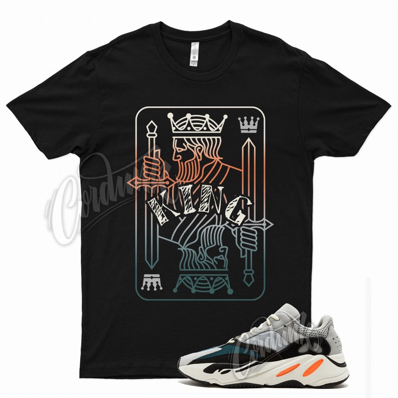 Puede incluir: Camiseta negra con un gr&aacute;fico de una carta de juego de rey de picas con un esquema de color vintage. La camiseta se combina con zapatillas blancas, grises, verdes y naranjas.