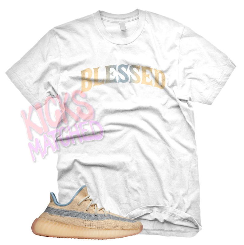 K&ouml;nnte beinhalten: Ein wei&szlig;es T-Shirt mit dem Wort "Blessed" in Regenbogenfarben bedruckt. Ein Paar hellbraune und blaue Turnschuhe mit wei&szlig;er Sohle.