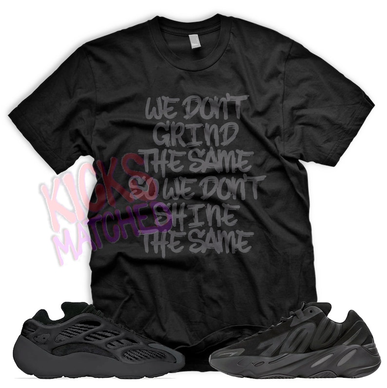 May include: Black t-shirt with the text "We don't grind the same so we don't shine the same" printed on it. A pair of black Yeezy 700 sneakers are also pictured.