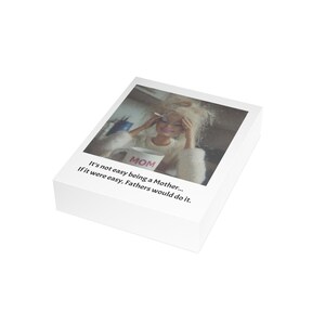 K&ouml;nnte beinhalten: Eine wei&szlig;e Box mit einem gedruckten Bild einer Frau, die eine Tasse mit der Aufschrift "MOM" h&auml;lt. Das Bild hat den Text "It's not easy being a Mother... If it were easy, Fathers would do it."