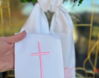 May include: A white fabric sash featuring an embroidered simple cross in baby pink thread. The text White Fabric Simple Cross Baby Pink Thread is visible at the top of the image. The sash is made of a smooth white material with a clean finish.