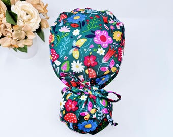 May include: Green scrub hat with a colorful floral and butterfly print. The hat has a tie at the back.